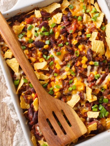 Overhead image of a Frito Pie with a wooden spatula on top