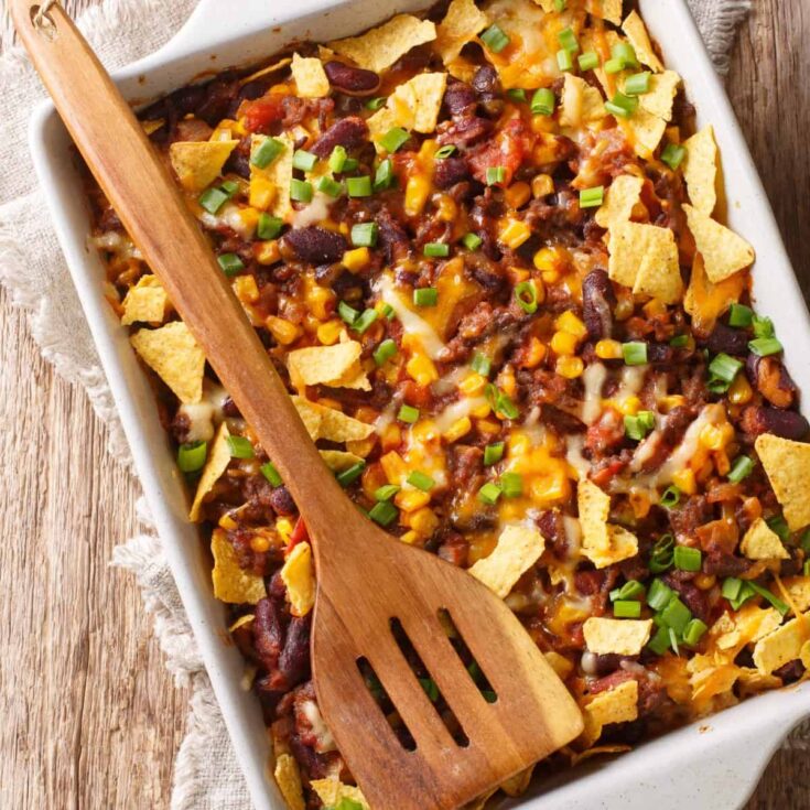 Overhead image of a Frito Pie with a wooden spatula on top
