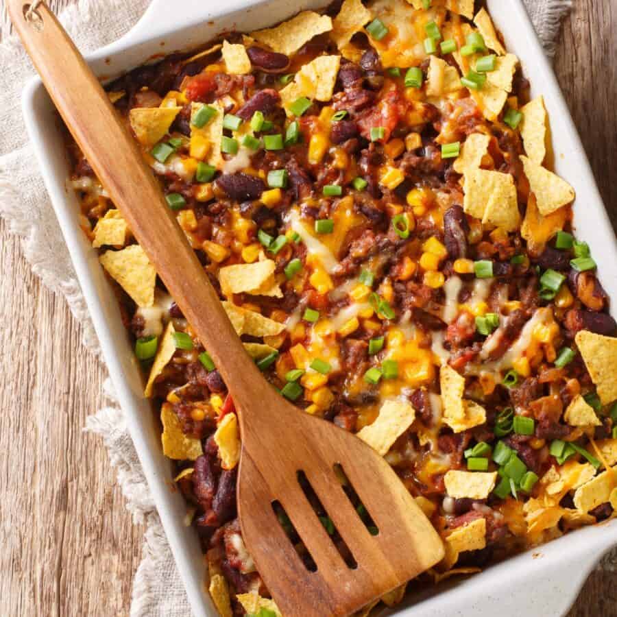 Overhead image of a Frito Pie with a wooden spatula on top