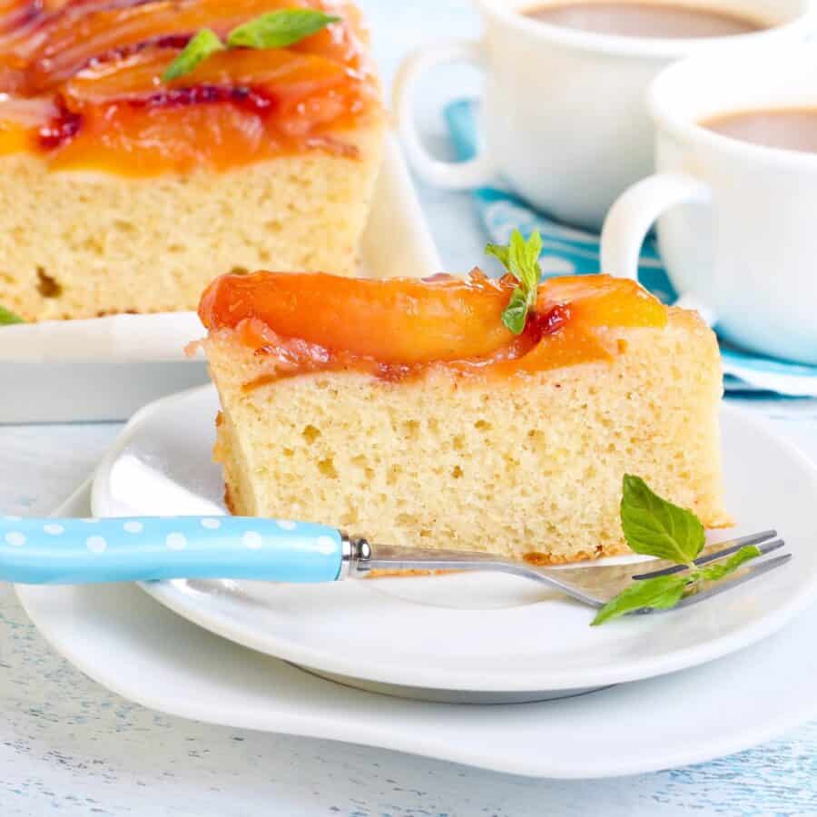 A slice of Peach Upside Down Cake on a plate with a fork