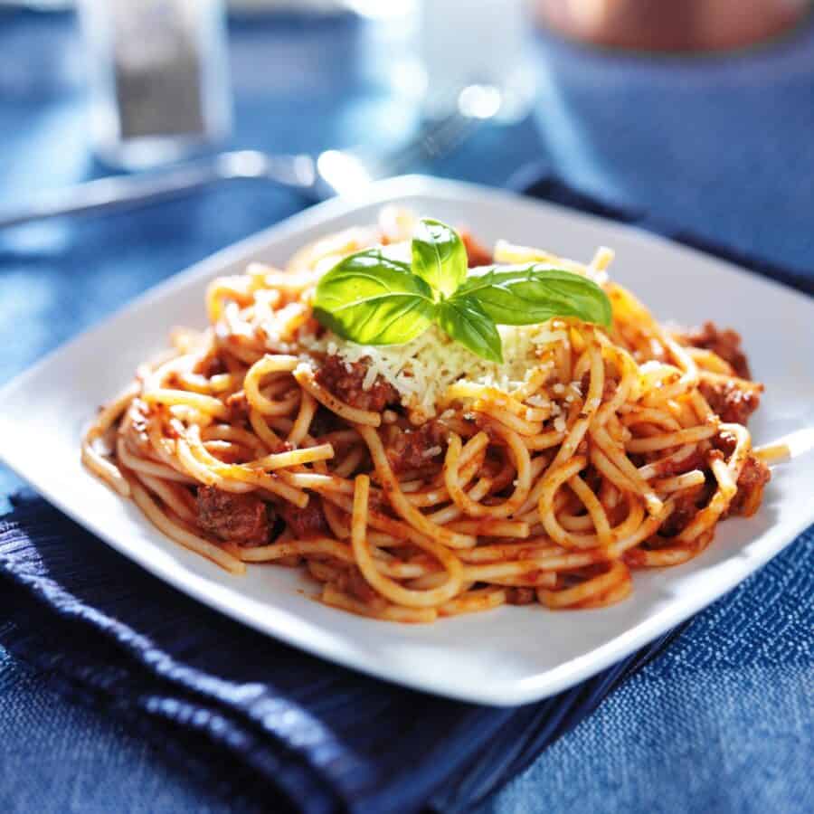Overhead image of Sausage Spaghetti on a white plate with a blue background