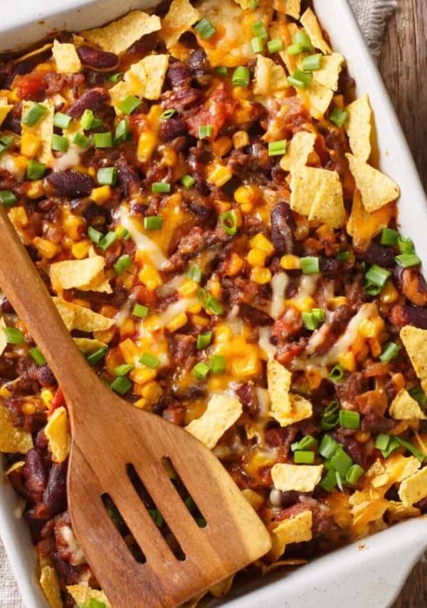 Overhead image of a Frito Pie with a wooden spatula on top