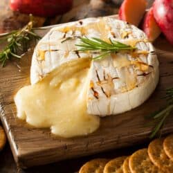 Close up image of Baked Brie on a wooden cutting board