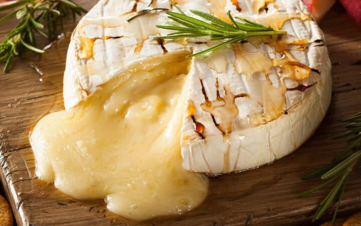 Close up image of Baked Brie on a wooden cutting board