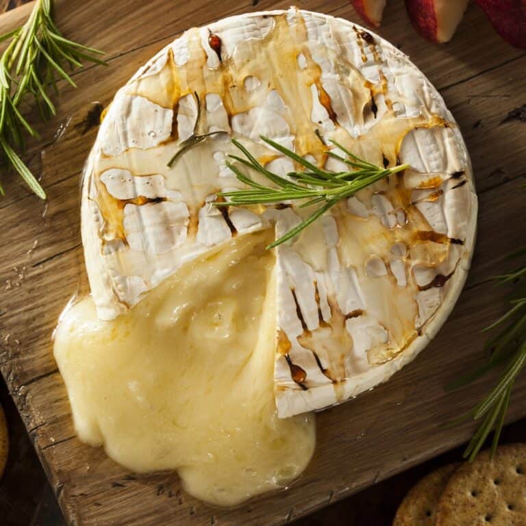 Overhead image of Baked Brie with a slice cut out of it on a cutting board
