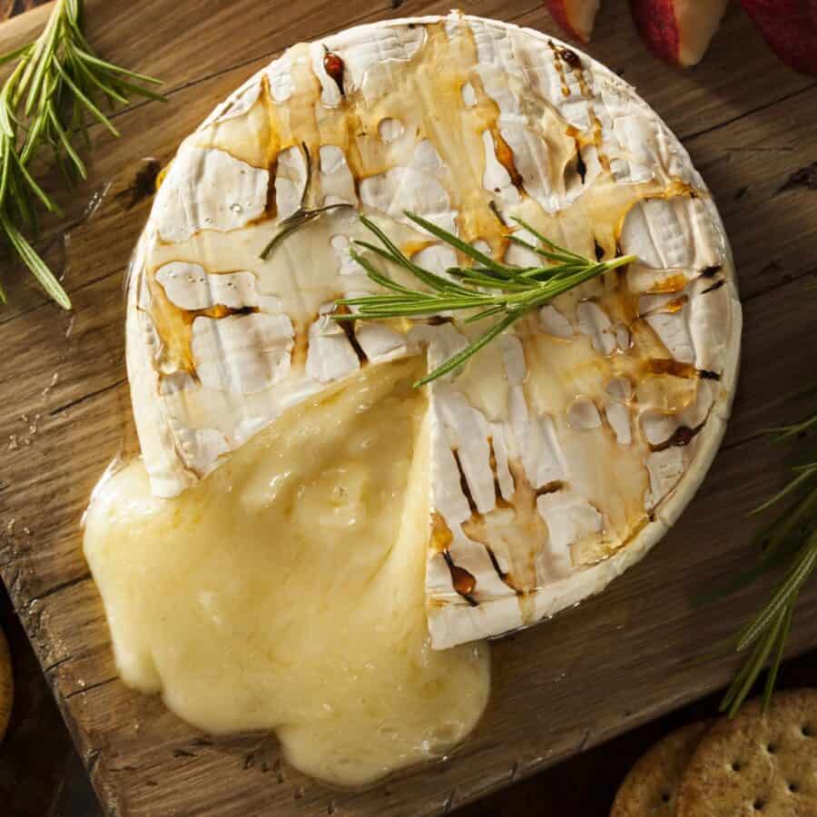 Overhead image of Baked Brie with a slice cut out of it on a cutting board