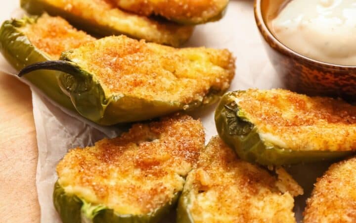 Close up image of Baked Jalapeno Poppers on parchment paper with dipping sauce
