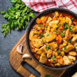 Slow Cooker Chicken Stew in a round dish with fresh herbs and garlic