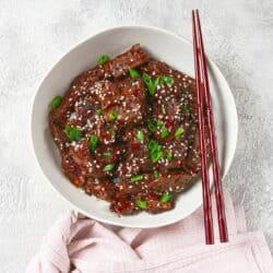 Overhead image of crispy beef in a white bowl with chopsticks