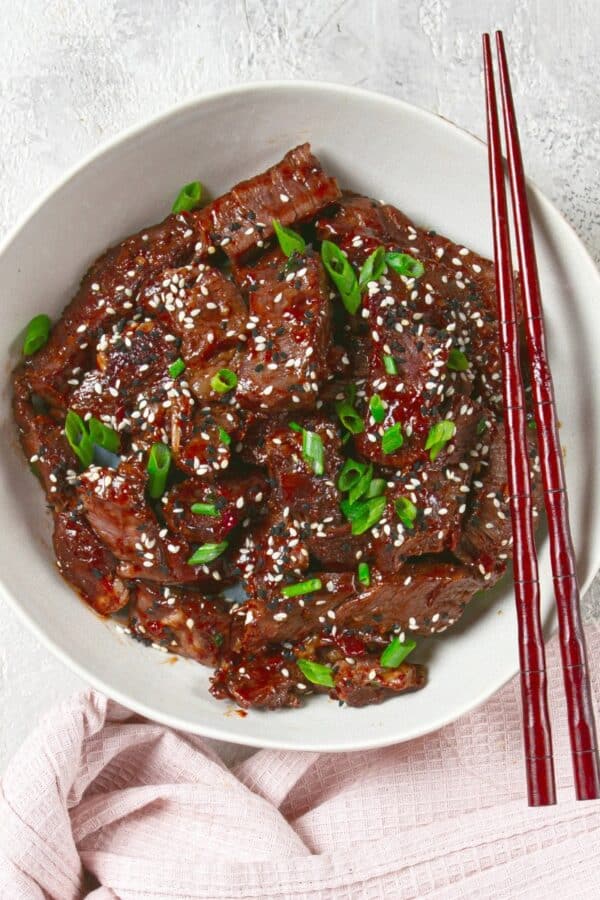 Overhead image of crispy beef in a white bowl with chopsticks