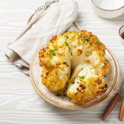 Overhead image of a Whole Roasted Cauliflower cut into pieces on a plate