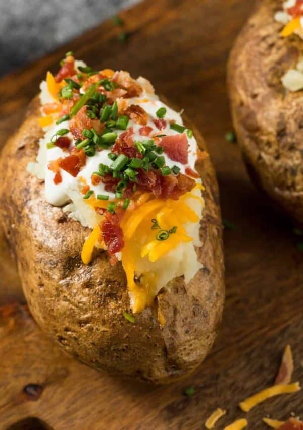 Two Jacket Potatoes with toppings on a wooden cutting board