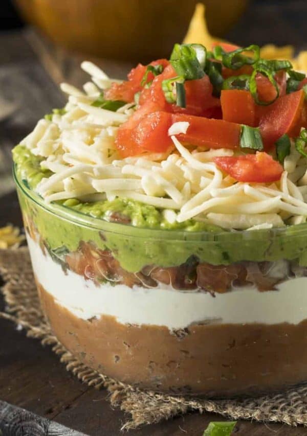 Close up image of Seven Layer Dip in a bowl on a rustic table