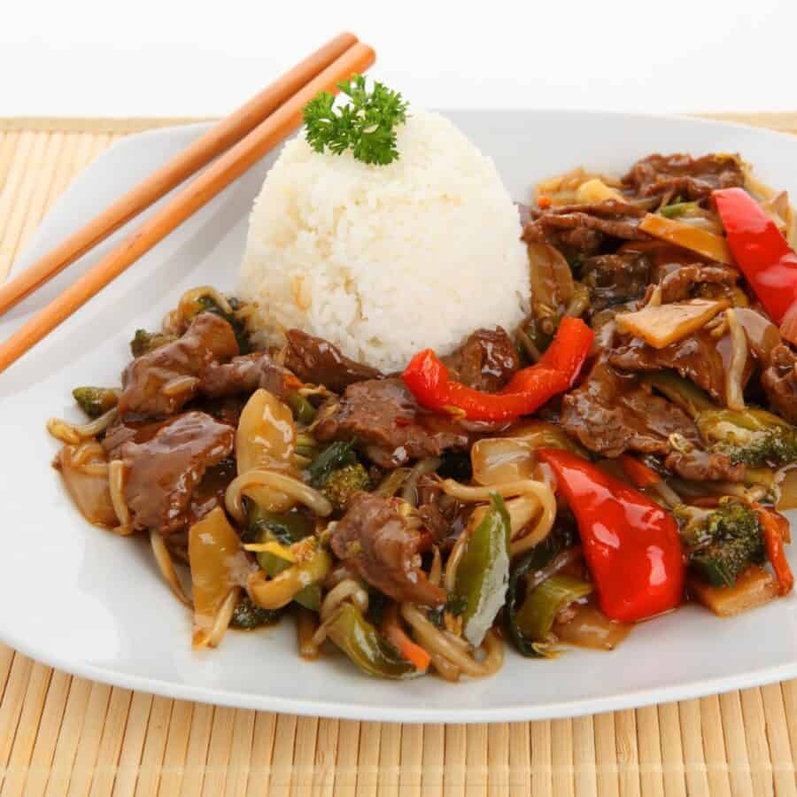 Beef Chop Suey on a white plate with rice and chopsticks