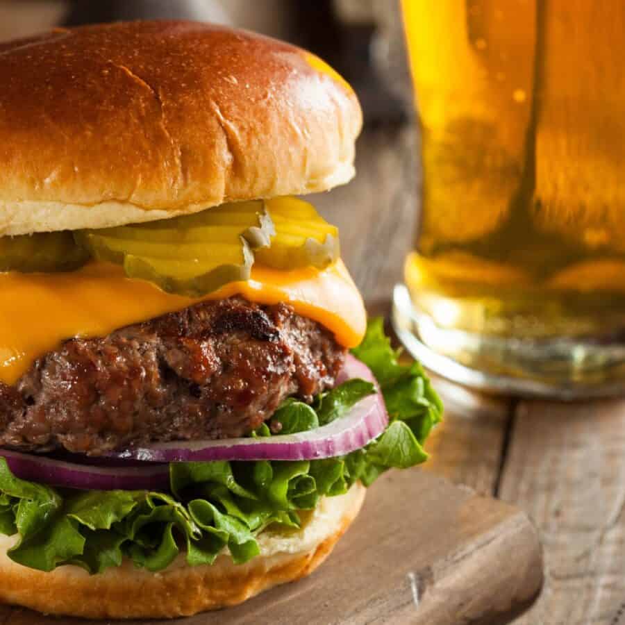 Close up image of a Bison Burger on a cutting board next to a beer