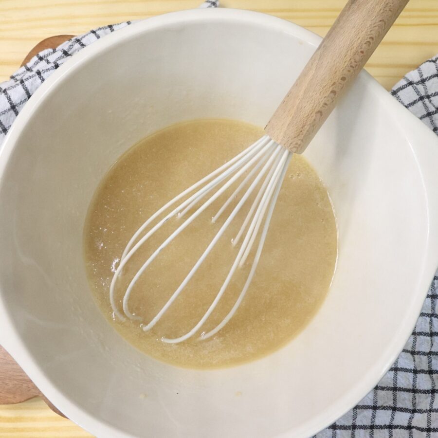 Wet ingredients for brownie batter dip in a mixing bowl with a whisk