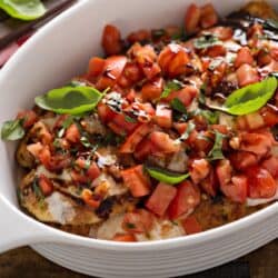 A pan of bruschetta chicken in a white baking dish