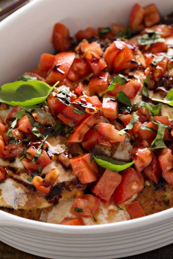 A pan of bruschetta chicken in a white baking dish