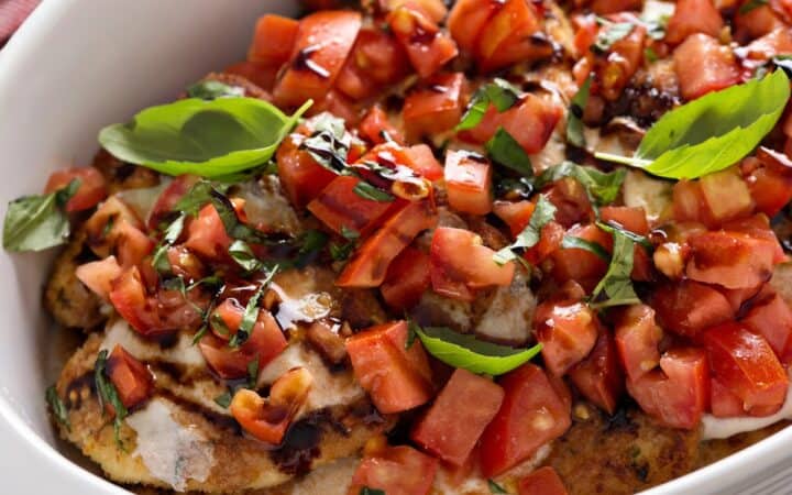 A pan of bruschetta chicken in a white baking dish