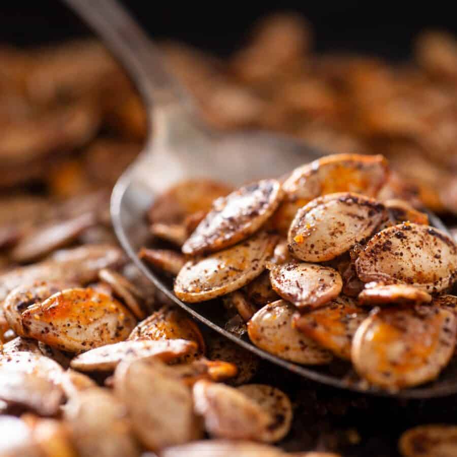 Roasted Pumpkin seeds on a spoon with more scattered under it