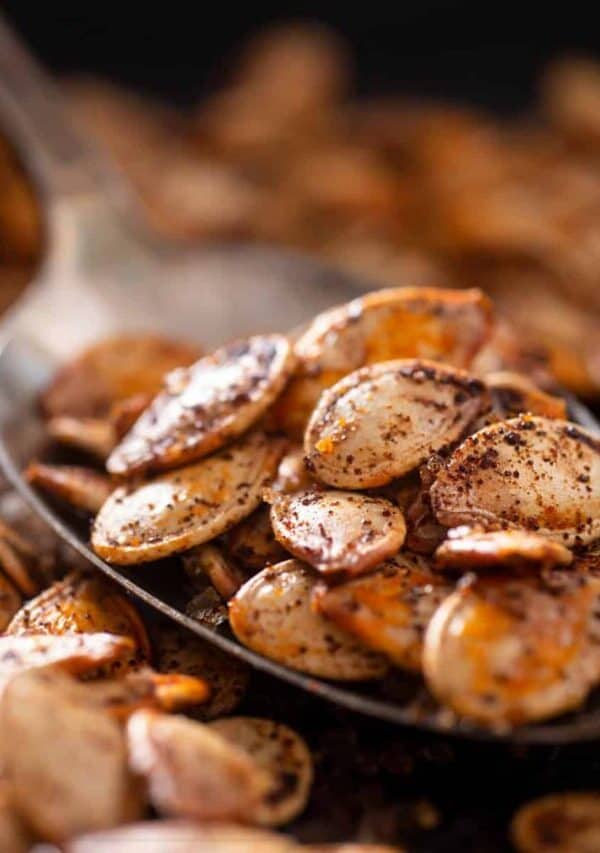 Roasted Pumpkin seeds on a spoon with more scattered under it