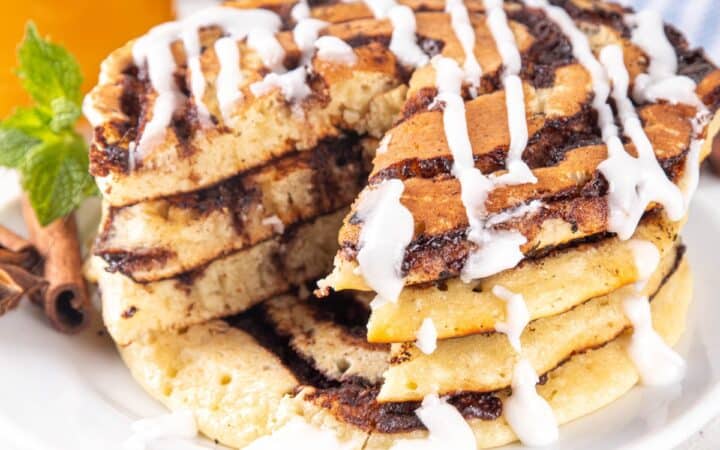 Close up image of Cinnamon Roll pancakes with a slice cut out of them
