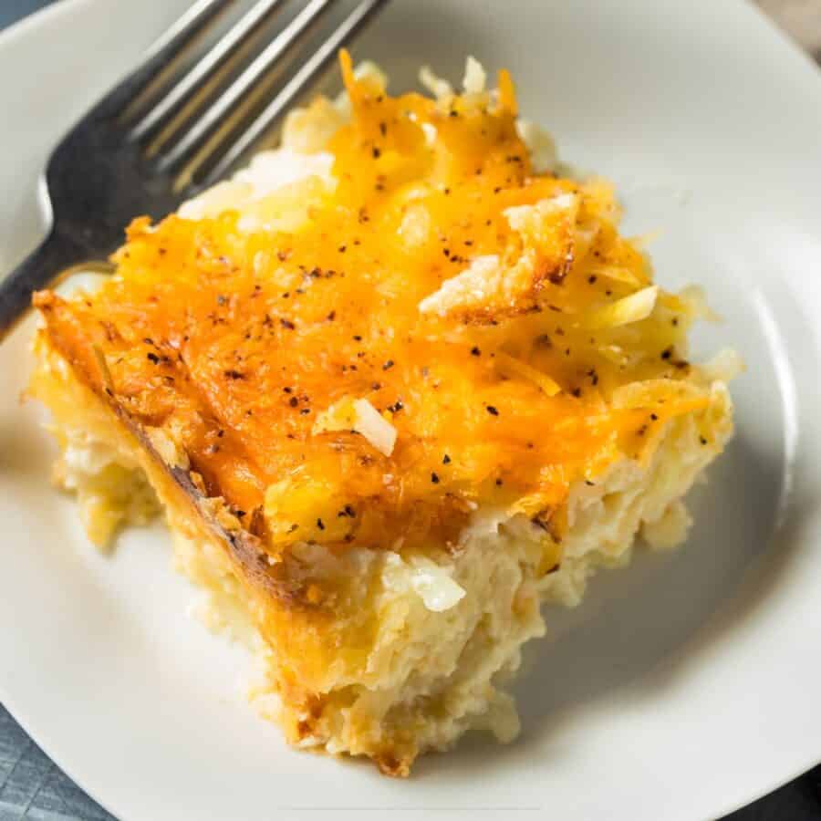 Close up image of a serving of hashbrown casserole on a white plate