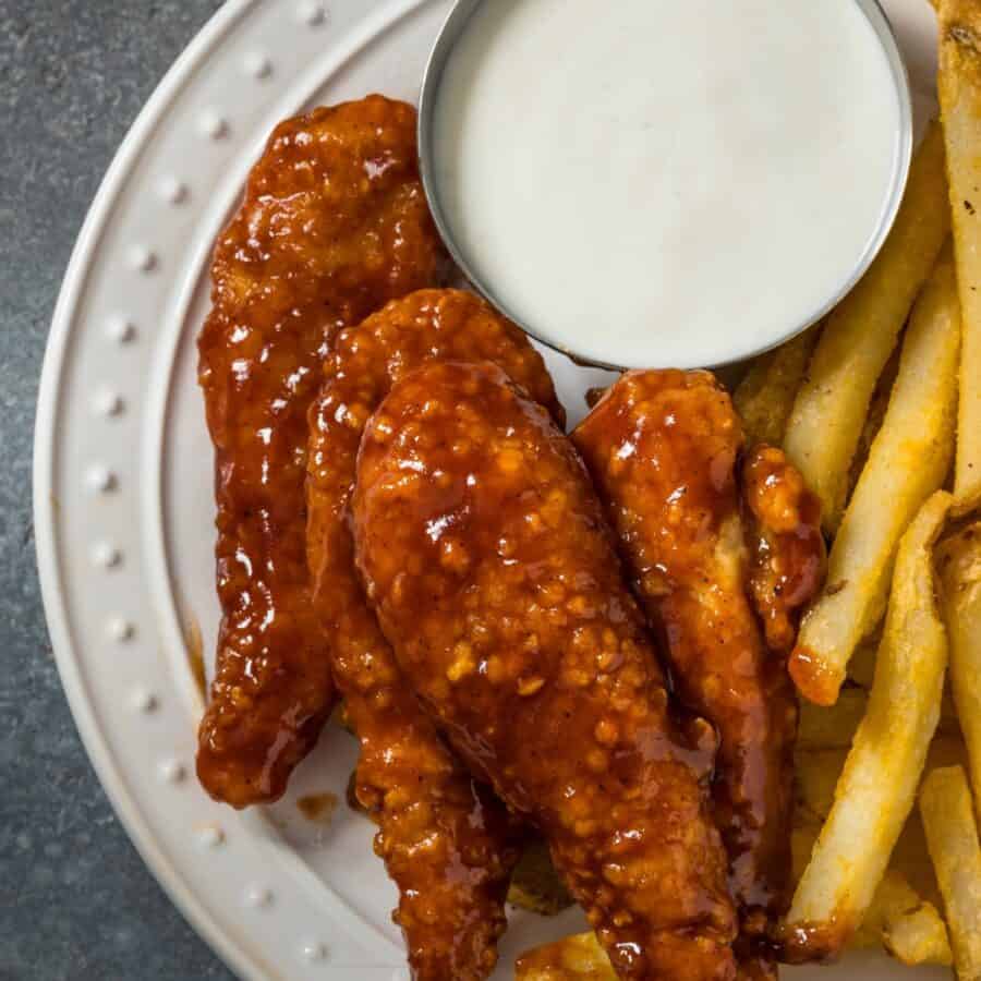 Overhead image of Honey BBQ Chicken Tenders on a white plate with fries and ranch