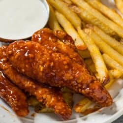 Close up image of Honey BBQ Chicken Tenders on a plate with fries and ranch dressing