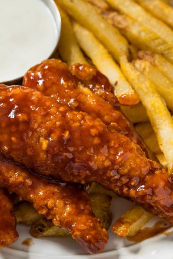 Close up image of Honey BBQ Chicken Tenders on a plate with fries and ranch dressing