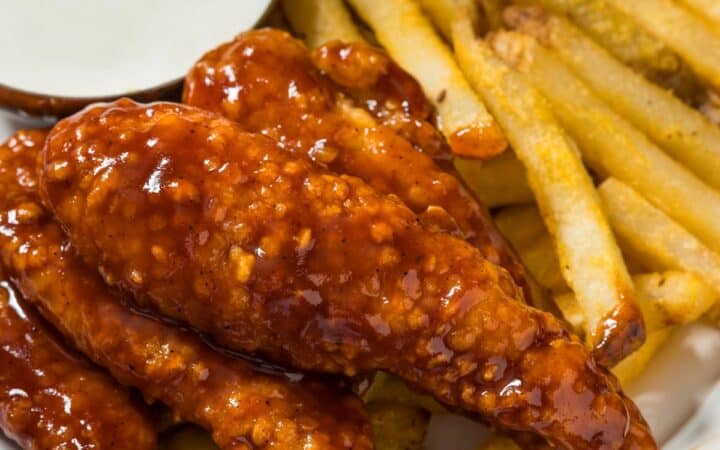 Close up image of Honey BBQ Chicken Tenders on a plate with fries and ranch dressing