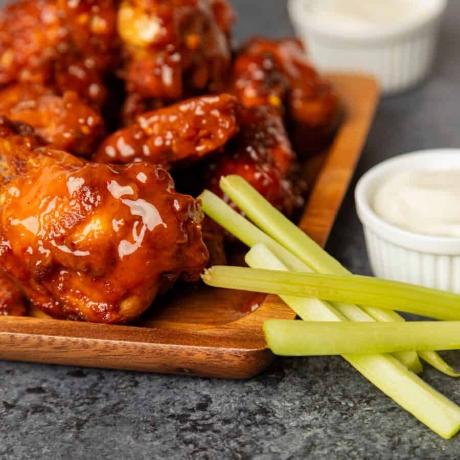 Close up image of Mango Habanero Wings on a wooden tray with celery and ranch