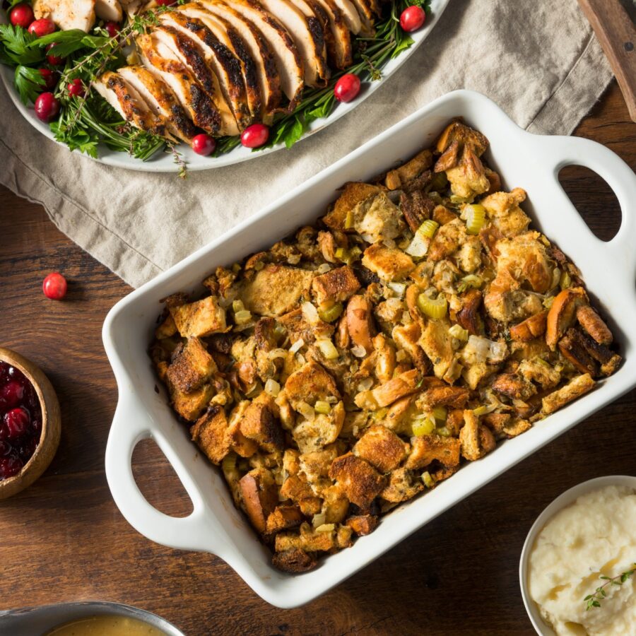 Overhead image of Sausage Stuffing in a baking dish next to sliced turkey