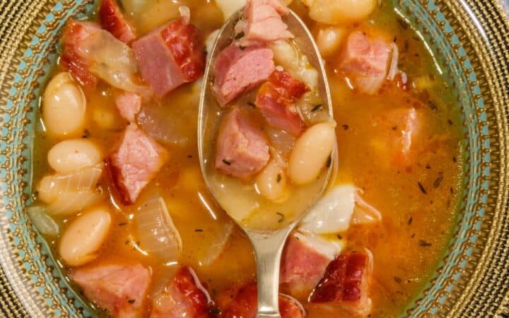 Overhead image of slow cooker ham and beans in a bowl with a spoon