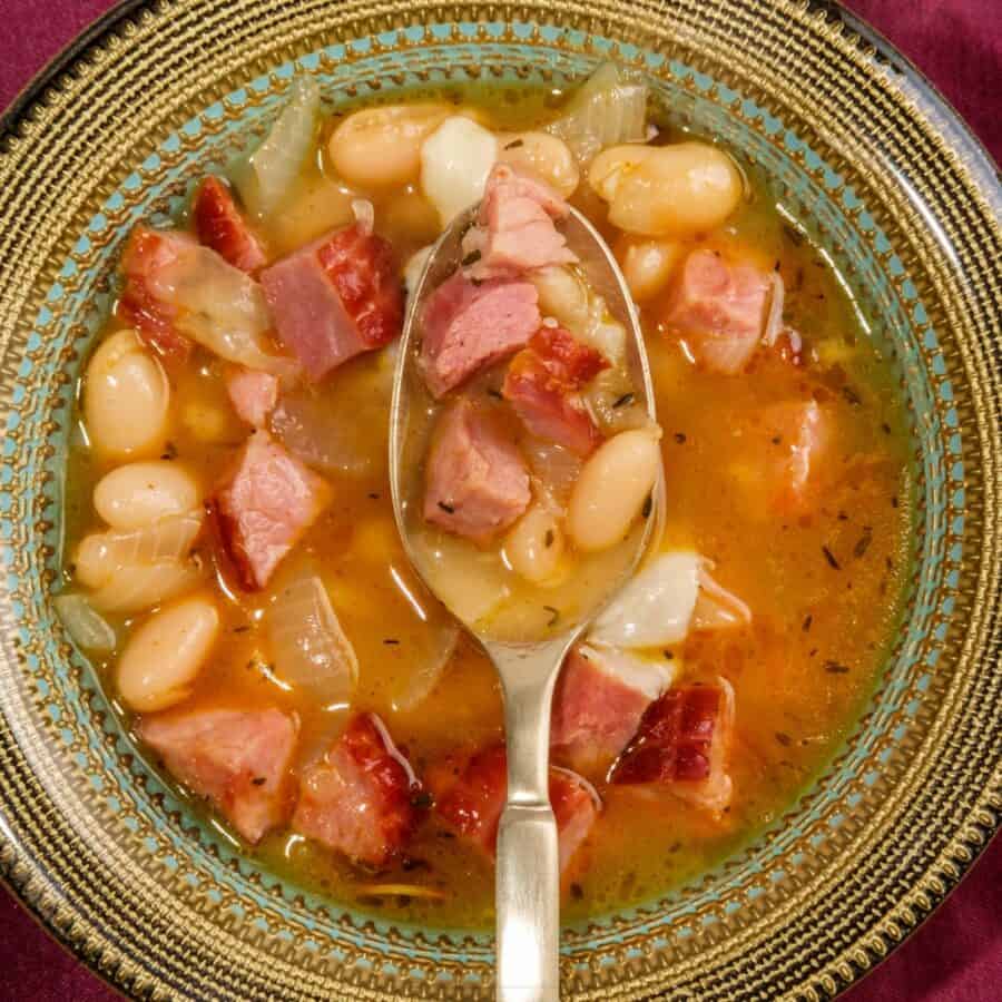 Overhead image of slow cooker ham and beans in a bowl with a spoon