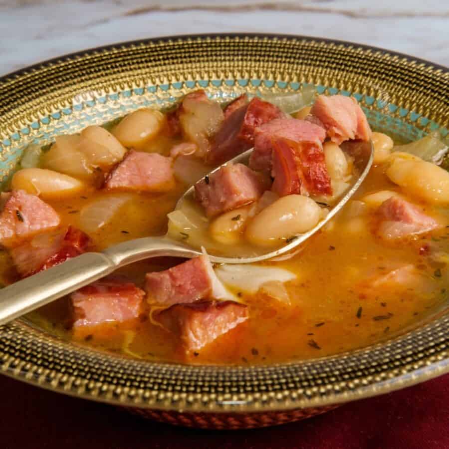 Close up image of slow cooker ham and beans being scooped up with a spon