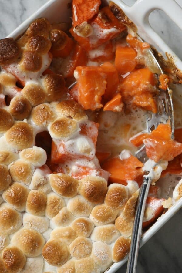 Overhead image of Sweet Potato Casserole with marshmallows with a serving taken out of it with a spoon