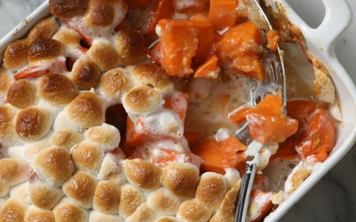 Overhead image of Sweet Potato Casserole with marshmallows with a serving taken out of it with a spoon