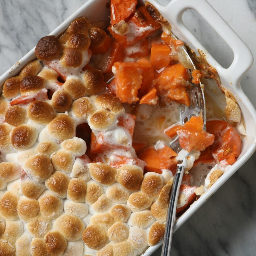 Overhead image of Sweet Potato Casserole with marshmallows with a serving taken out of it with a spoon