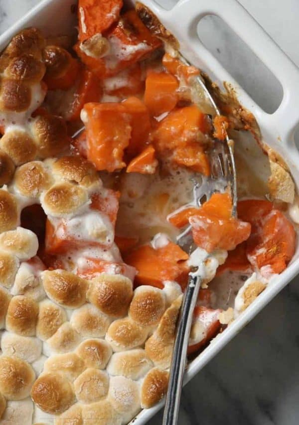 Overhead image of Sweet Potato Casserole with marshmallows with a serving taken out of it with a spoon