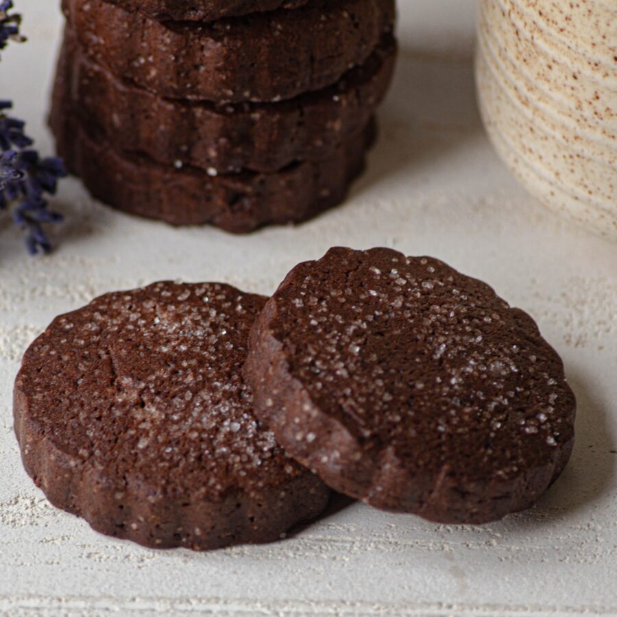 A stack of chocolate shortbread cookies with two laying in front of them