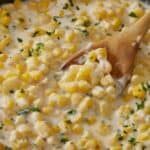 Overhead image of creamed corn in a skillet with a wooden spoon serving it - 9