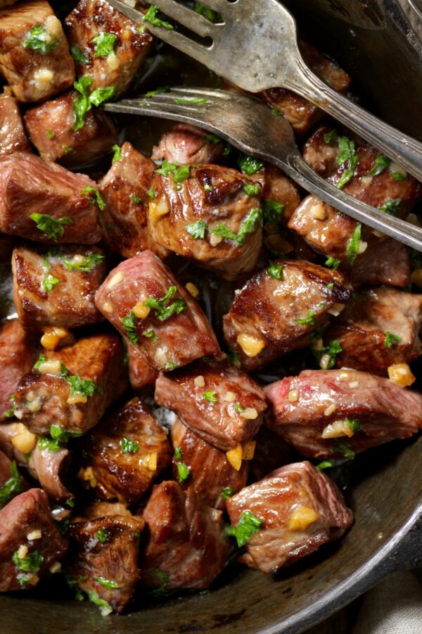 Close up image of slow cooker steak bites with cutlery in the dish