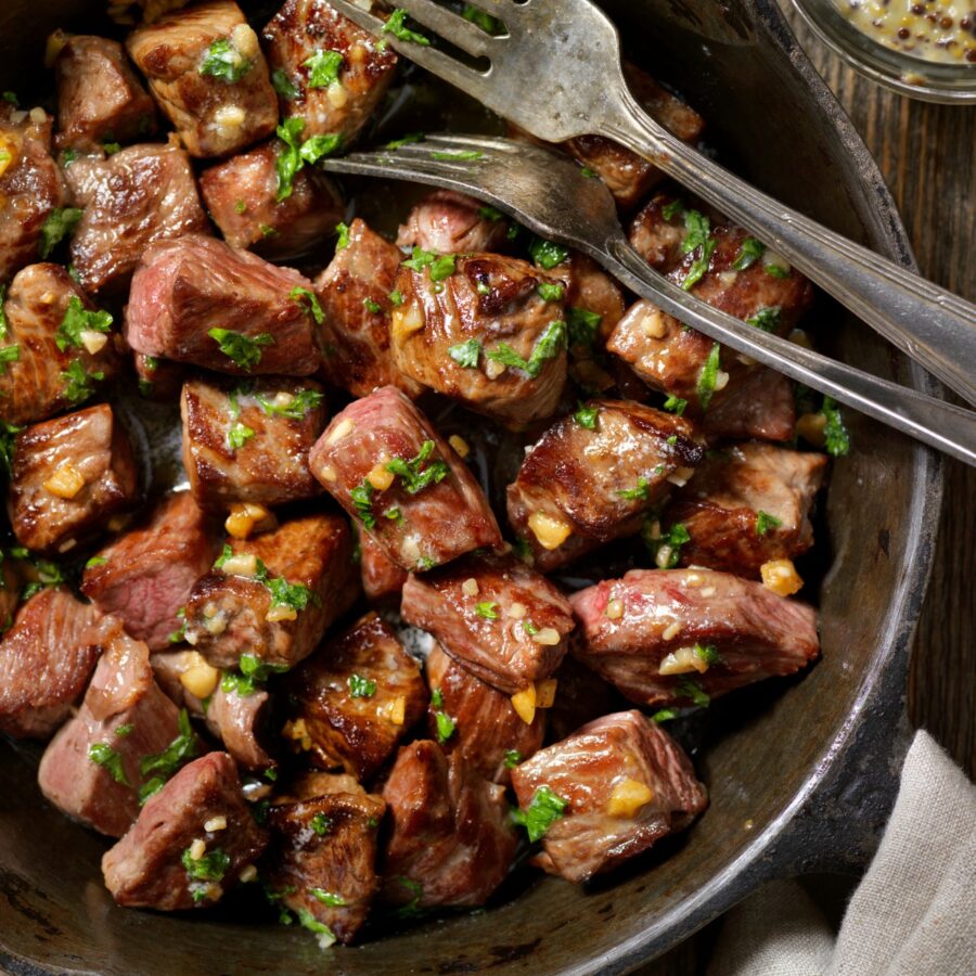Close up image of slow cooker steak bites with cutlery in the dish