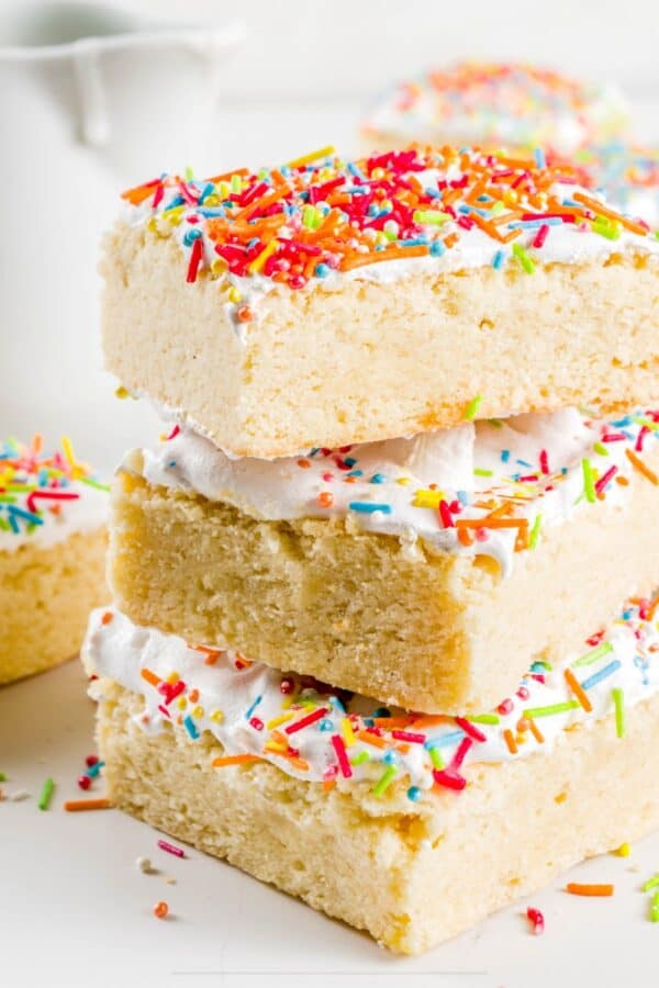 Sugar Cookie Bars stacked on top of eachother on a bright white surface