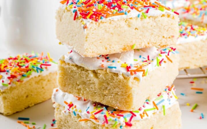 Sugar Cookie Bars stacked on top of eachother on a bright white surface