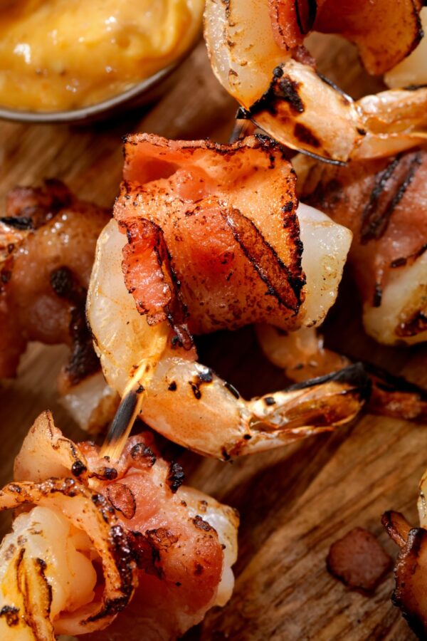 Bacon Wrapped Shrimp on a cutting board with a side of mustard