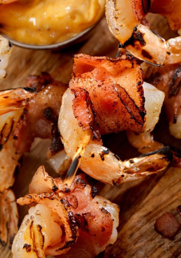 Bacon Wrapped Shrimp on a cutting board with a side of mustard