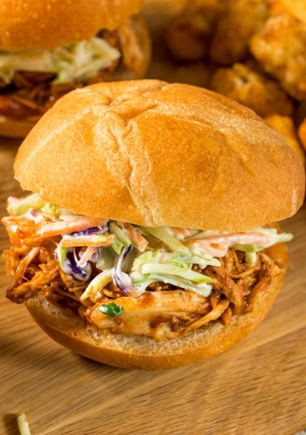 Close up image of a buffalo chicken slider with coleslaw on a wooden cutting board
