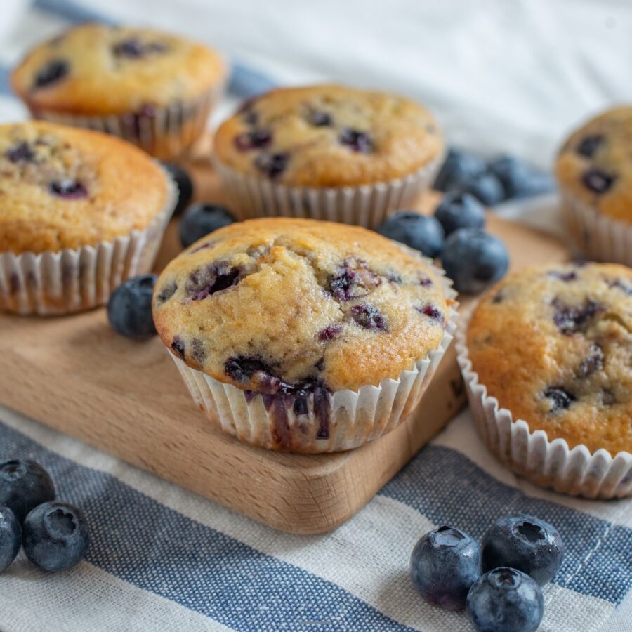Close up image of cottage cheese muffins on a cutting board with blueberries scattered